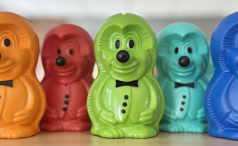 Hranilniki Ježki v različnih barvah, razvrščeni v vrsti na svetli površini.