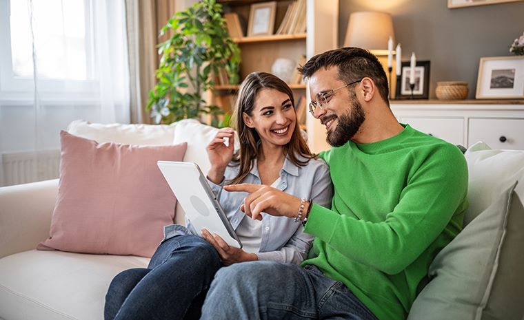 Mlad par v dnevni sobi gleda v tablični računalnik.