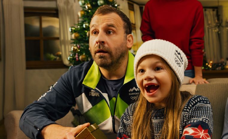 Oče in hči v božičnem vzdušju navijata za olimpijce in olimpijke