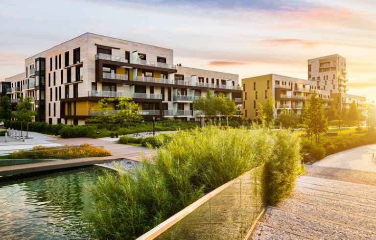 Sodoben stanovanjski kompleks. V ospredju se nahajajo zelene površine, ribniki in sprehajalne poti.