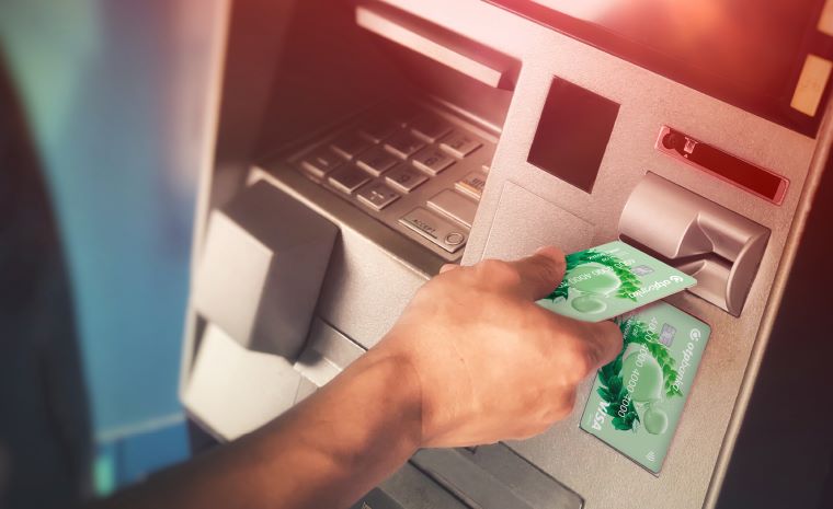 Oseba na bankomatu v režo za kartice vstavi kartico OTP banke. Bankomat ima tipkovnico, zaslon za izvajanje transakcij.