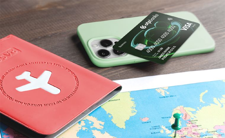 Rdeč potni list z belim letalom, zemljevid in pametni telefon, na njem pa poslovna debetna VISA kartica OTP banke Rdeč potni list z belim letalom, zemljevid in pametni telefon, na njem pa poslovna debetna VISA kartica OTP banke