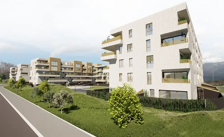 Stanovanjski kompleks Zlato polje z več belimi stanovanjskimi stavbami, ki imajo bež poudarke in več balkonov z rastlinami.