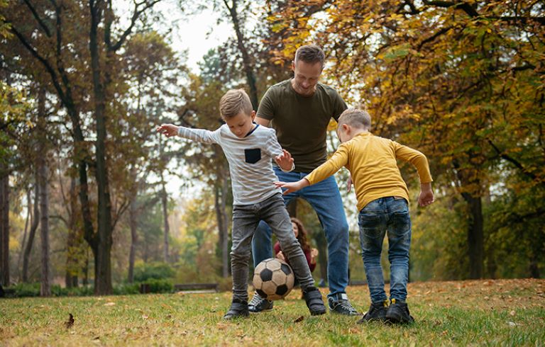 Družina igra nogomet na jasi v gozdu.